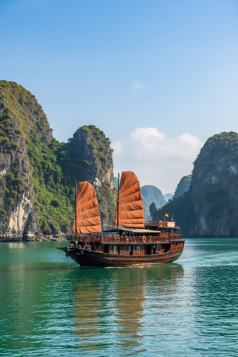 A junk under red sail among the karsts of Ha Long Bay