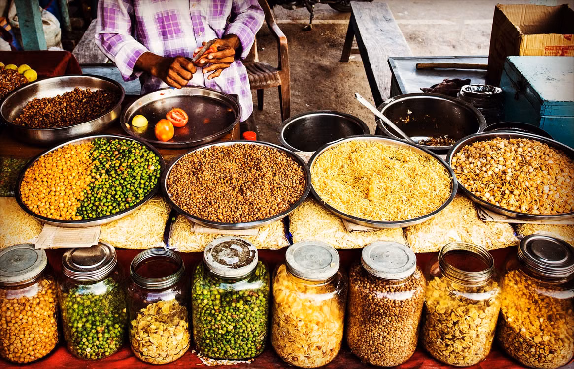 A spice stall with wide bowls of lentils and grains above rows of jars