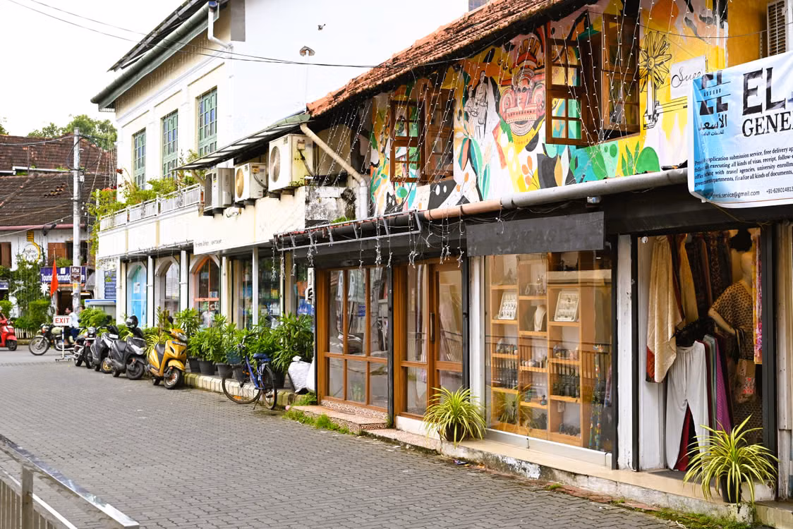 A Fort Kochi street of colourful murals, small shops and a tiled-roof house