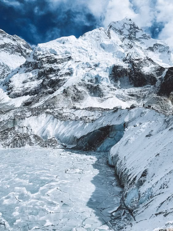 A snow-covered glacier below mountain peaks