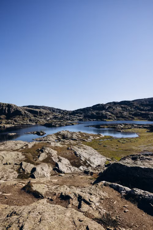 A rocky shore and still lake under a clear sky