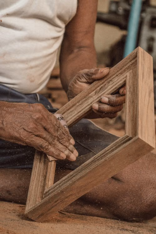 Hands fitting together a carved wooden frame