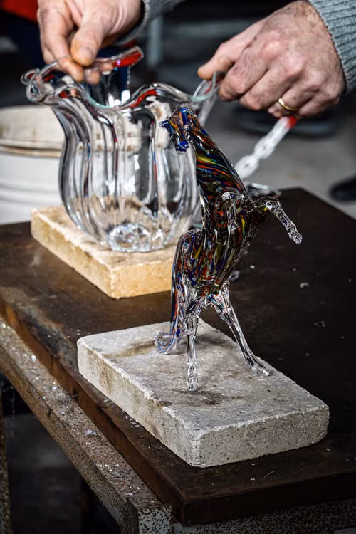 Glassmakers shaping a clear glass horse