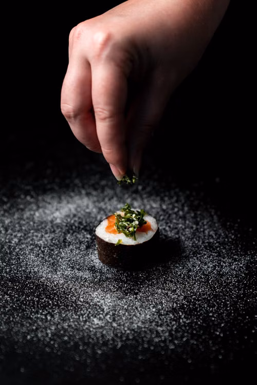A hand finishing a single plated dish with a garnish