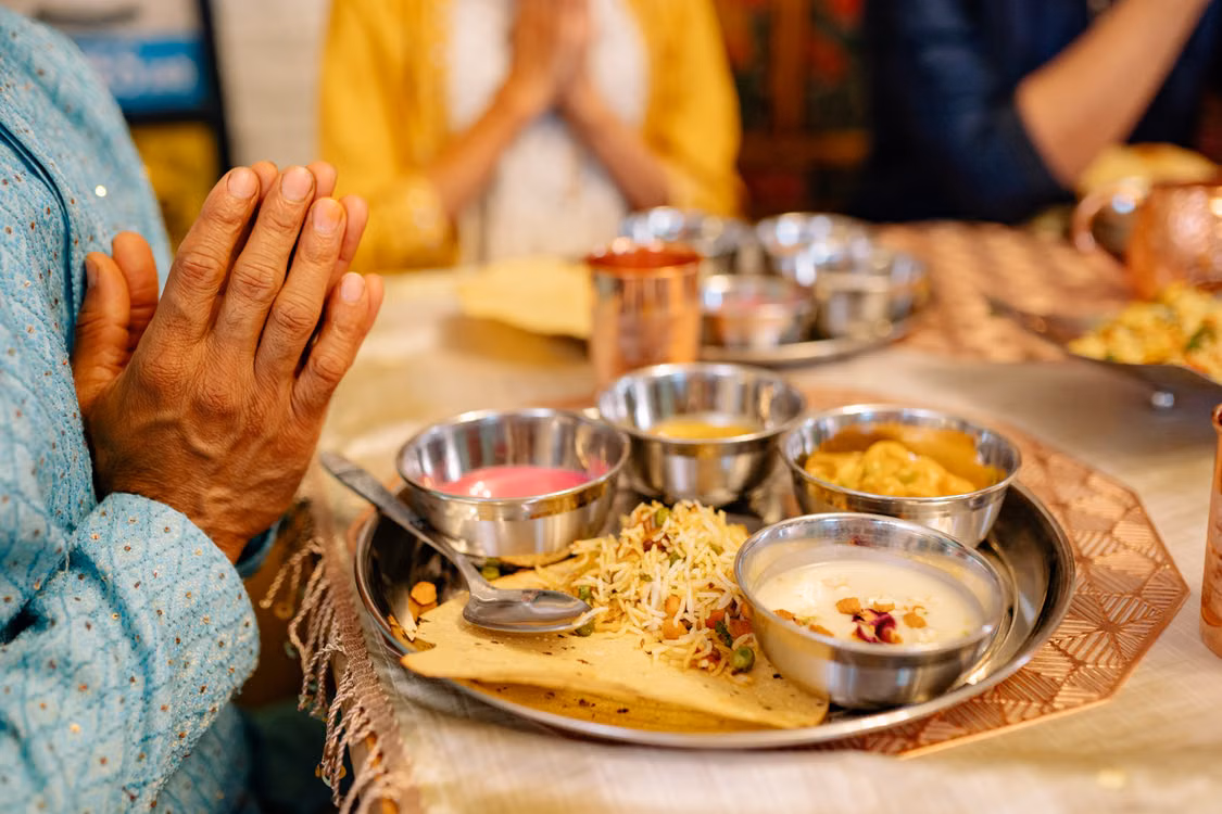 A hand resting beside a table laid with silver dishes of food