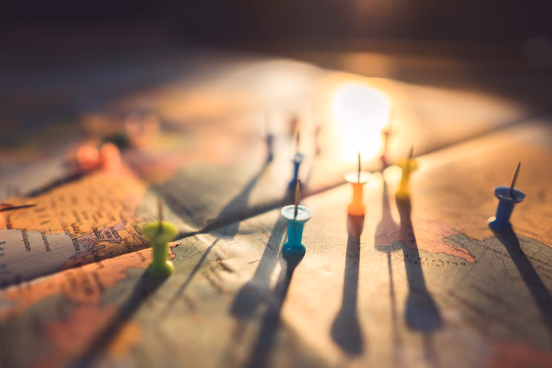Pins pushed into a map, lit by warm light