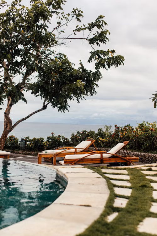 Sun loungers beside a pool overlooking green hills