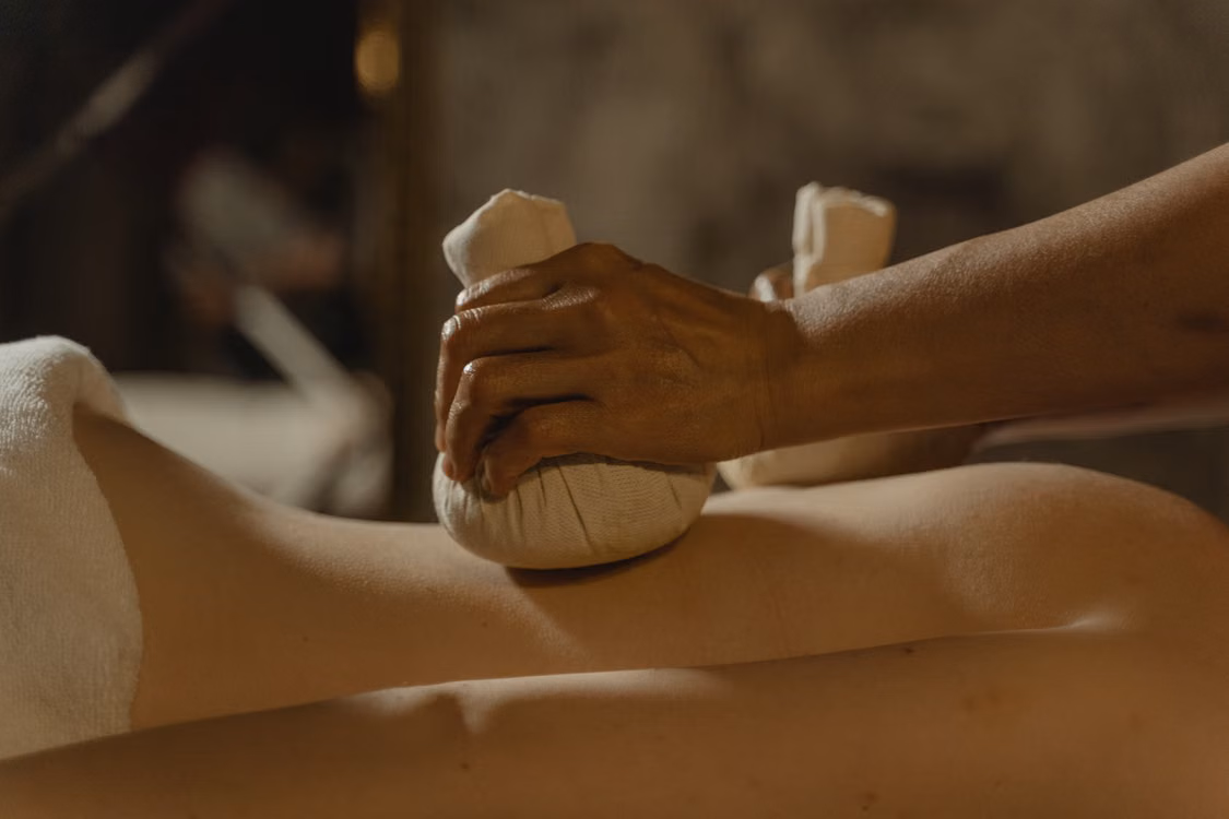 A herbal compress being pressed against a leg during a treatment