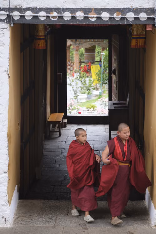 Two young monks in red robes in a monastery doorway