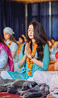 Women in marigold garlands seated with their hands in prayer