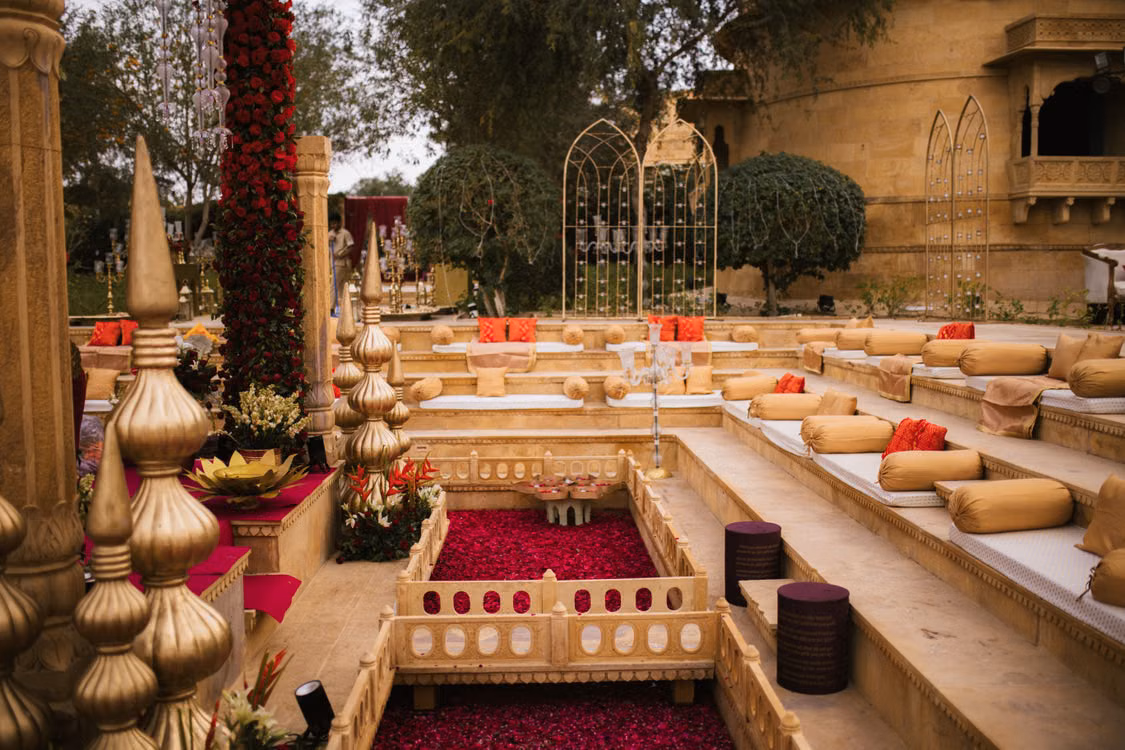 A marigold-draped palace courtyard with cushioned seating and rose-petal pits, Rajasthan