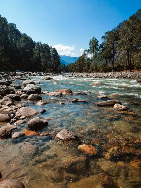A clear river running over boulders in the Kullu Valley