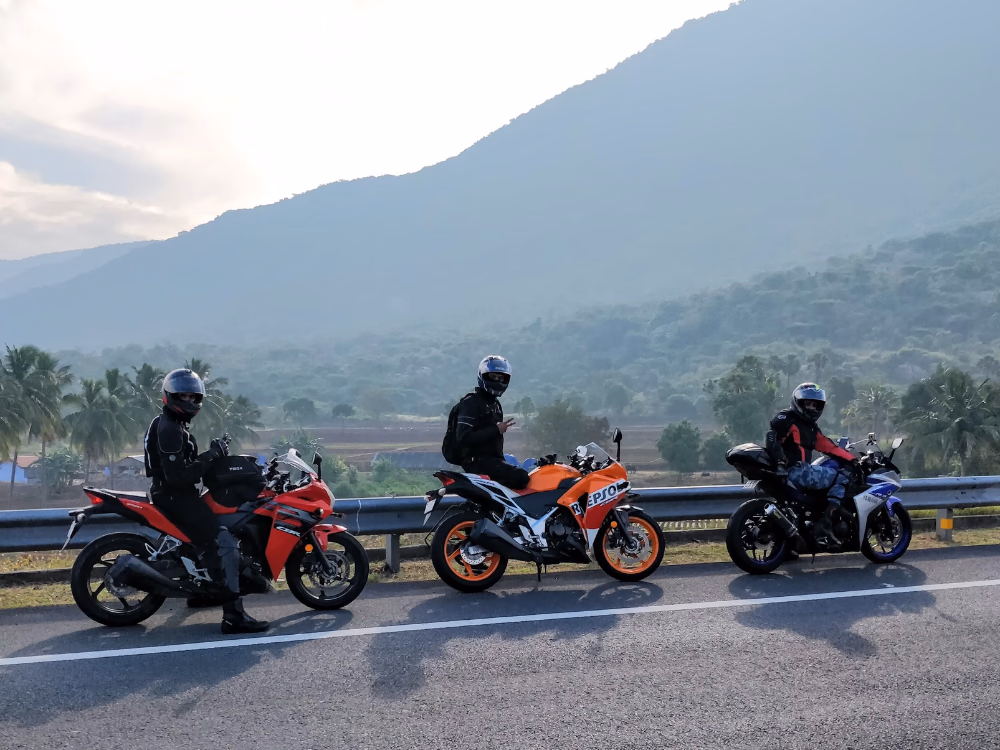 Three riders on sport motorcycles beside a mountain road in Thailand