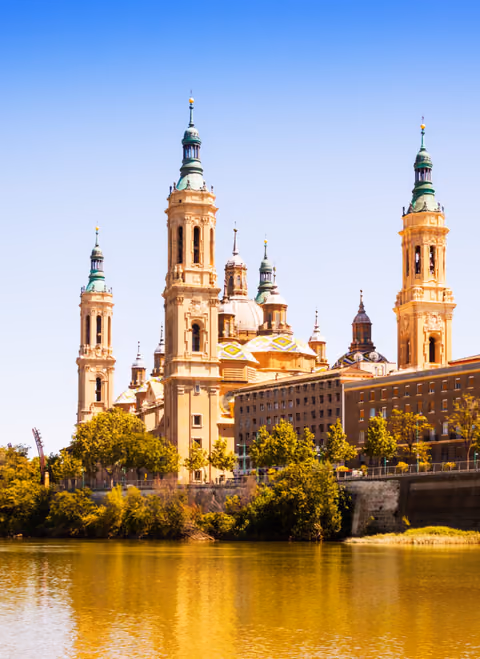 Twin bell towers of a baroque basilica above a golden riverfront