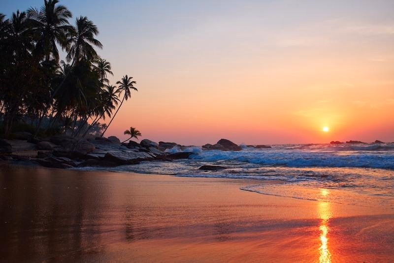 The sun setting over a rocky South Goa beach