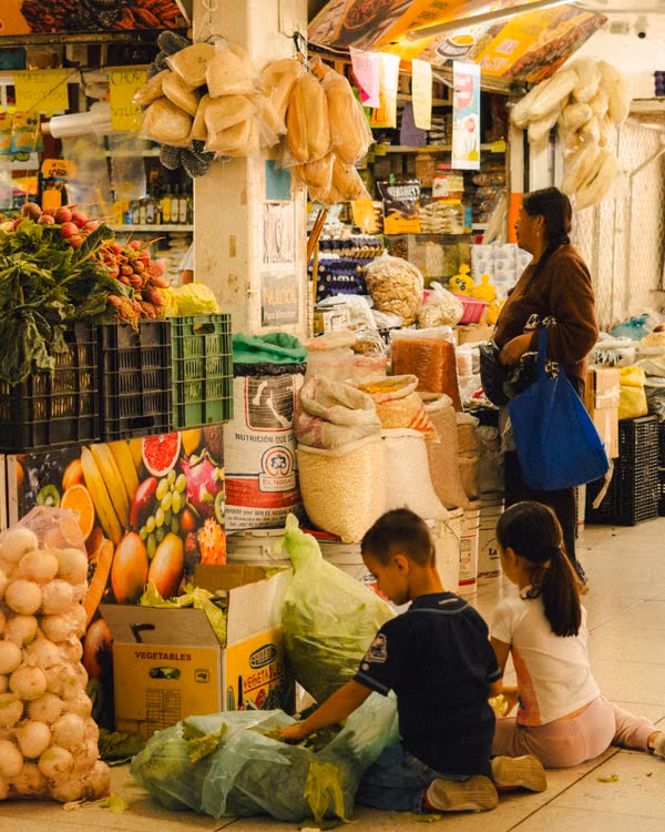 Shoppers and a child at a busy fruit and vegetable market