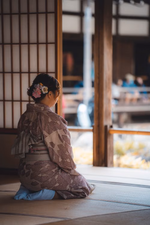 A woman in a kimono kneeling on a wooden floor