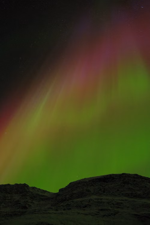 A green aurora above a dark hill