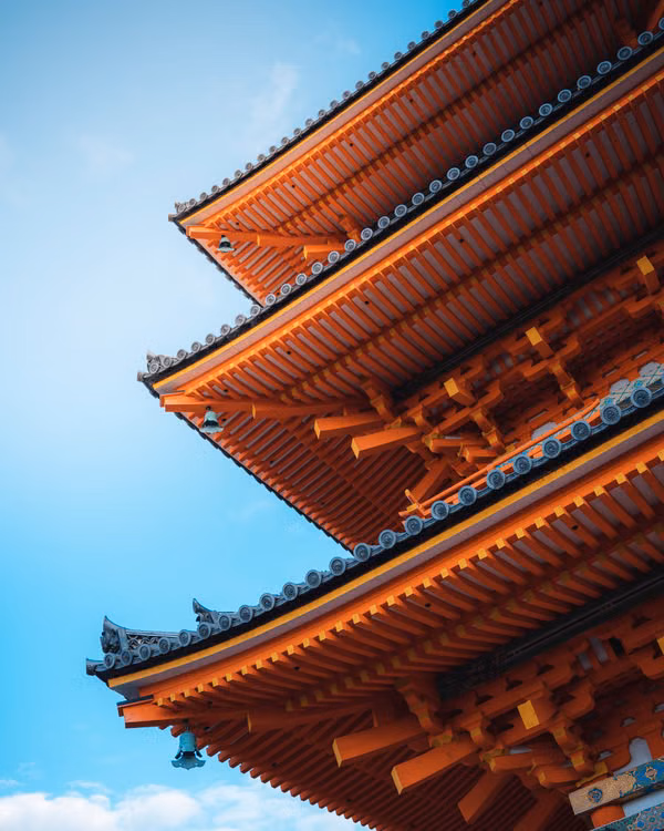 The tiered orange roofs of a pagoda against a blue sky